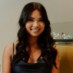 A woman in a black dress smiling while making a cashless payment at a store.